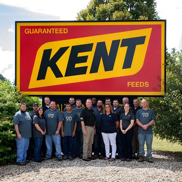 photo of employees with Gage Kent in front of plant sign